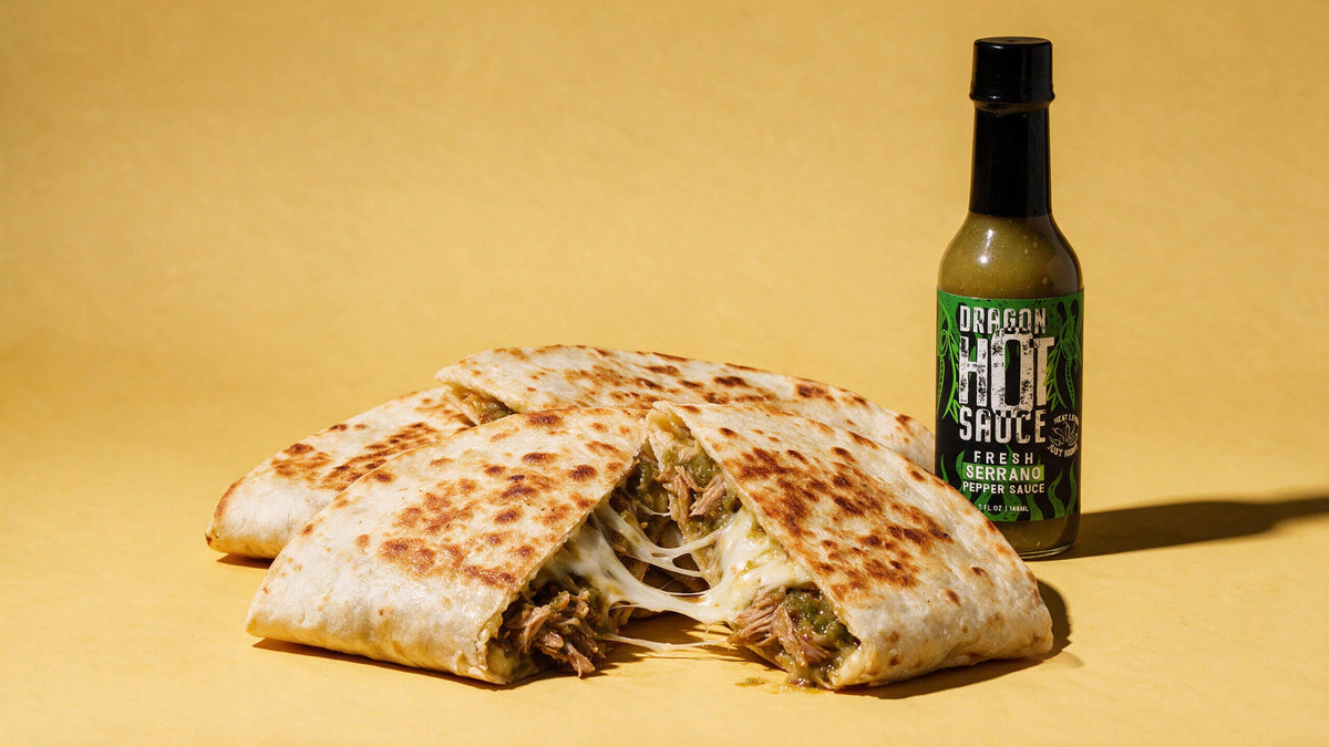Crispy salsa verde pork quesadillas cut open with melted cheese, next to a bottle of Dragon Fresh Serrano.