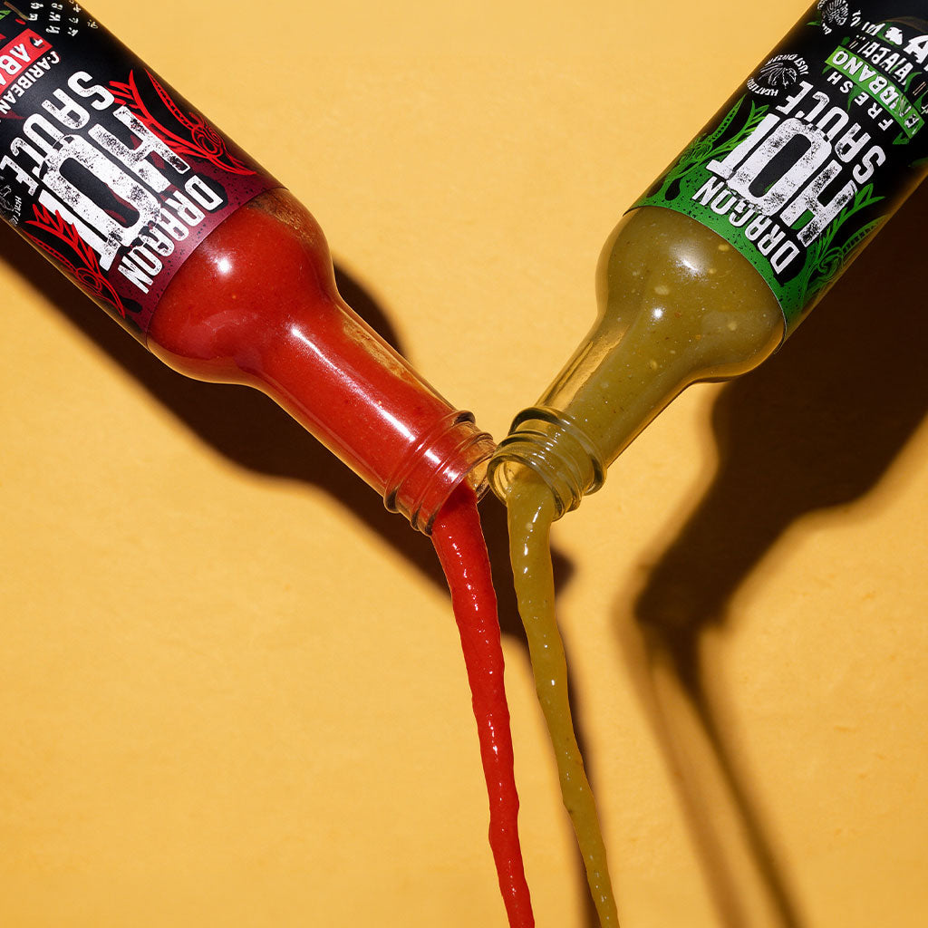 Dragon Caribbean Style Habanero and Fresh Serrano bottles tipped together, pouring red and green hot sauce